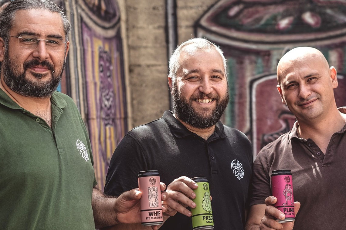 Tre persone del birrificio calabrese Funky Drop mostrano lattine di birra